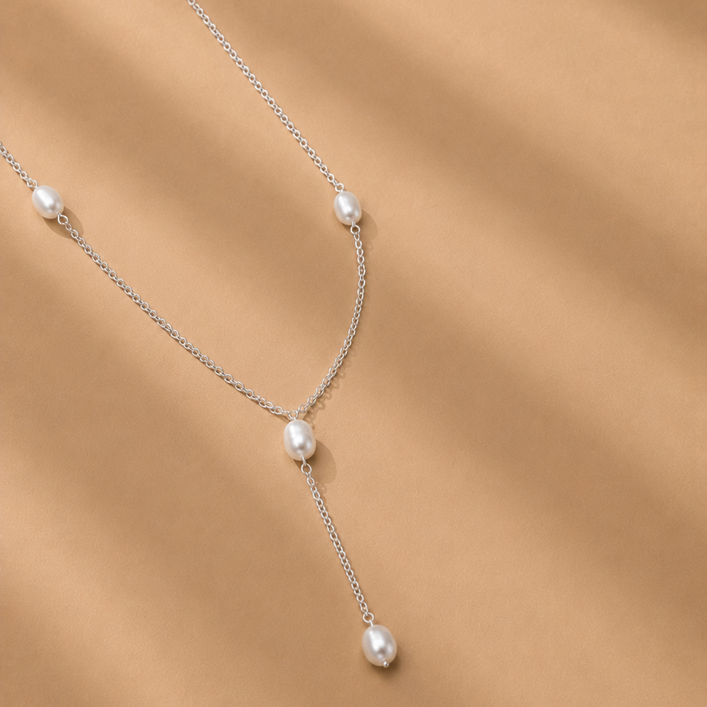 The Nubia Necklace by Ryā Atelier features 6mm freshwater pearls spaced along a sterling silver chain and pearl drop