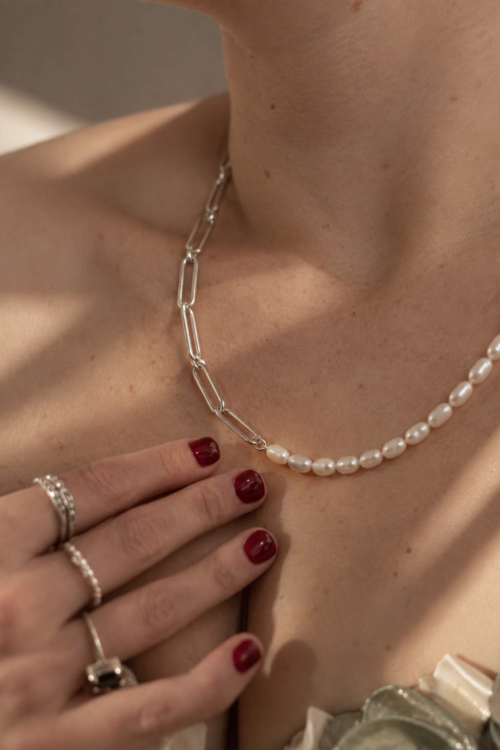 Close up of a model wearing The Ayanda Necklace by Ryā Atelier features a solid sterling silver handmade paperclip chain and a string of delicate freshwater pearls. 