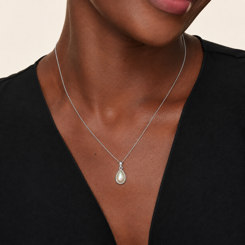Model wearing the medium sized Inyembezi Pendant from Ryā Atelier. The pendant features a teardrop-shaped Mabe pearl set in a solid sterling silver bezel 