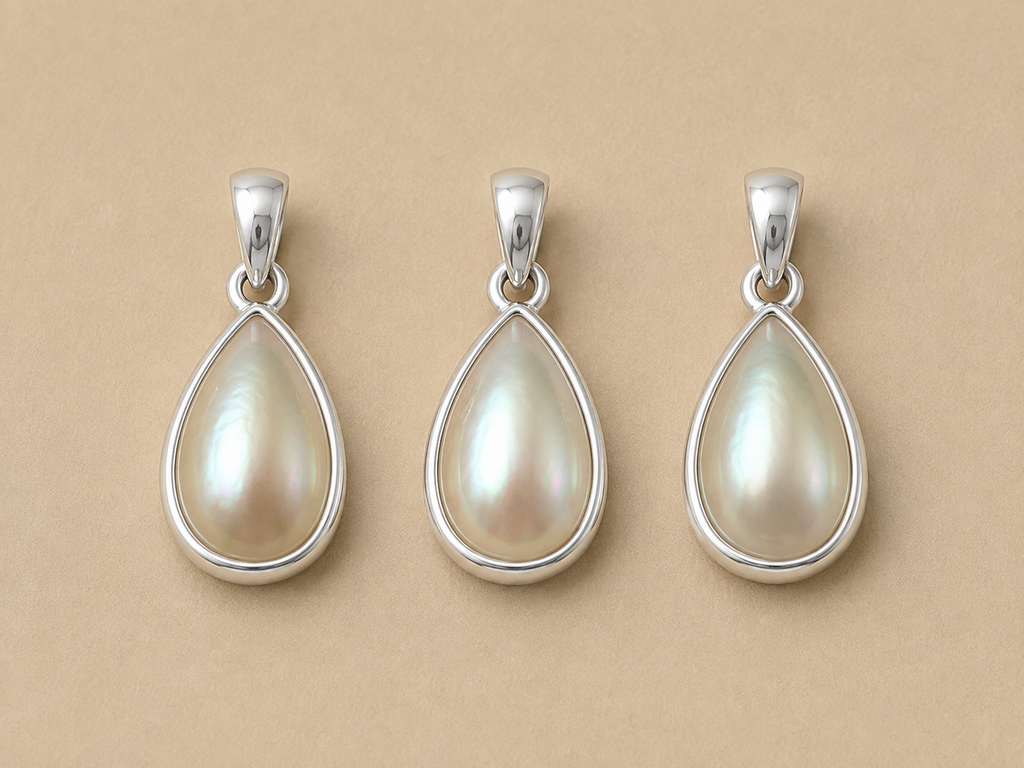 Three matching medium sized Inyembezi pendants from Rya Atelier. Each pendant features a teardrop shaped mabe pearl set in a solid sterling silver bezel. 