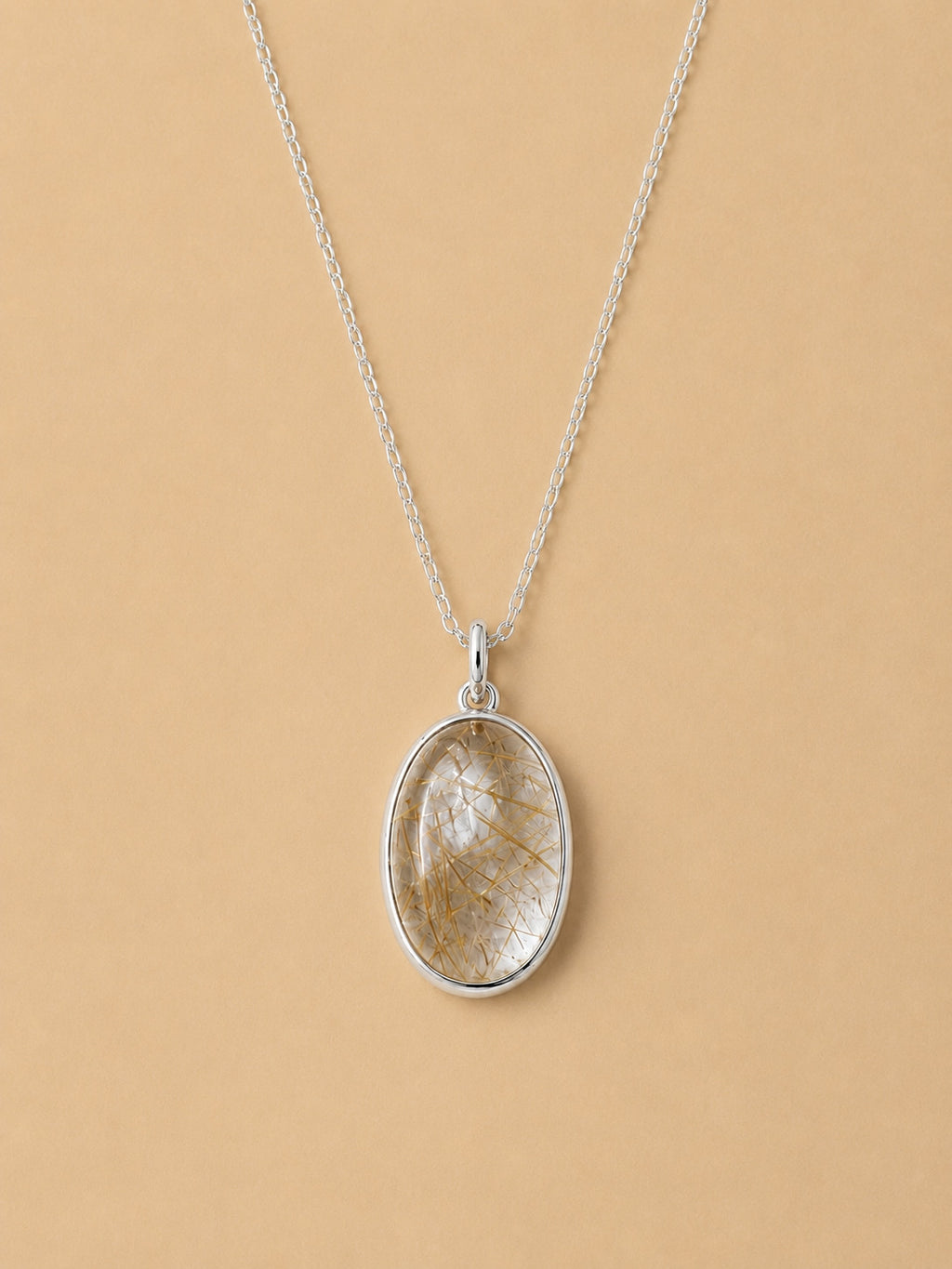 Sterling Silver Necklace with an oval natural rutilated quartz pendant on a beige background