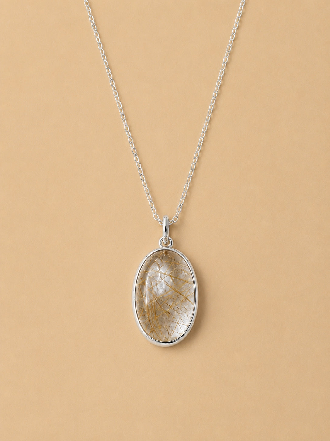 Sterling Silver Necklace with an oval natural rutilated quartz pendant on a beige background