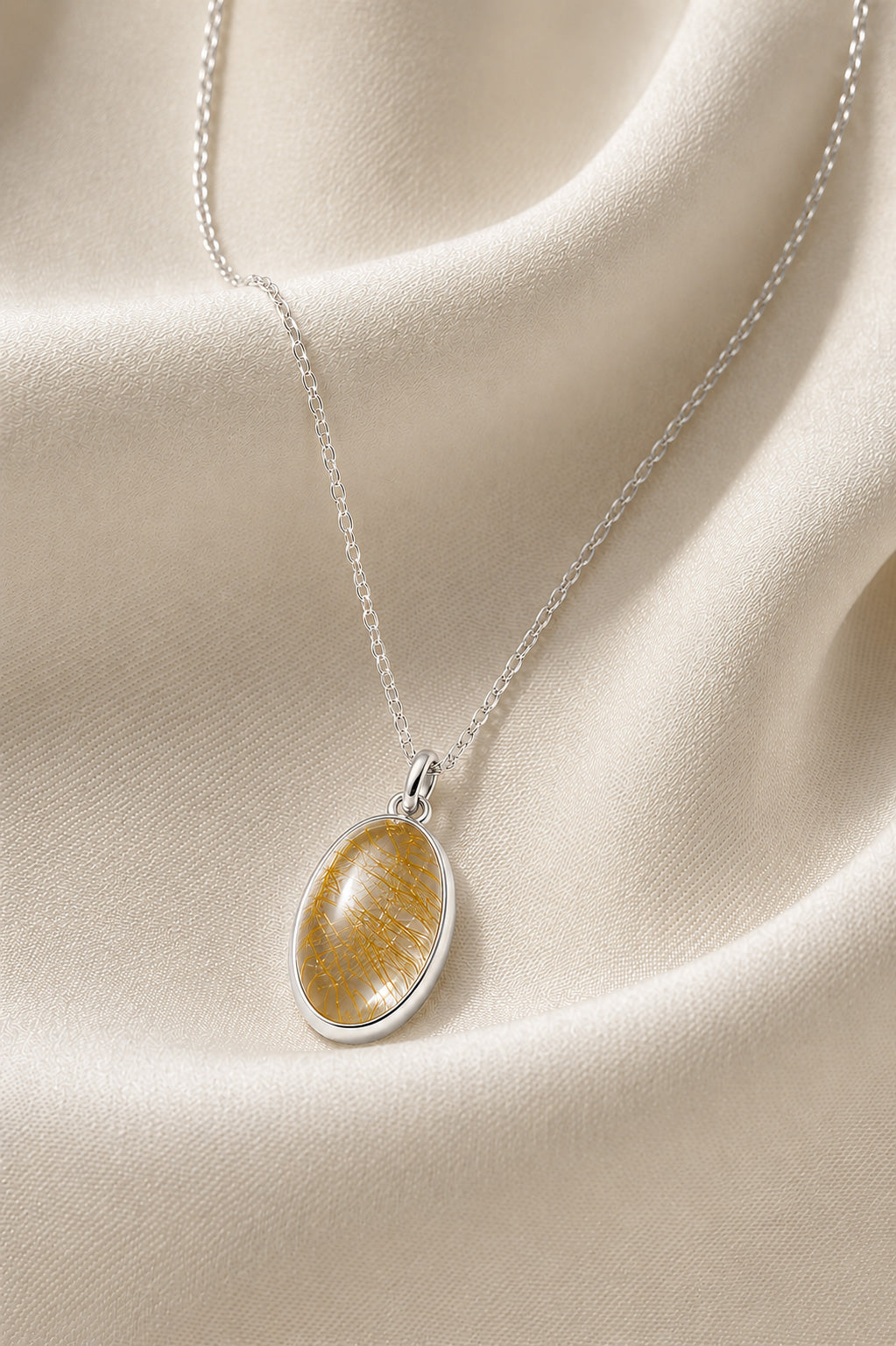 Sterling silver Silver necklace with a natural oval rutilated quartz  pendant on beige fabric