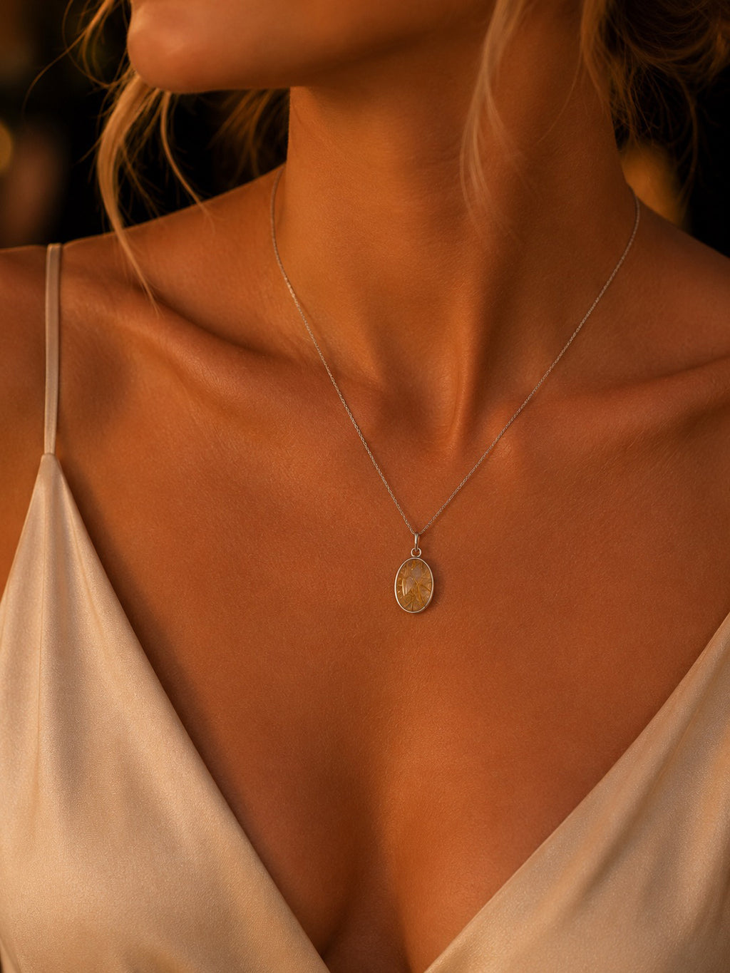 Sterling Silver Necklace with a natural rutilated quartz pendant on a person wearing a white top, with a warm, blurred background.