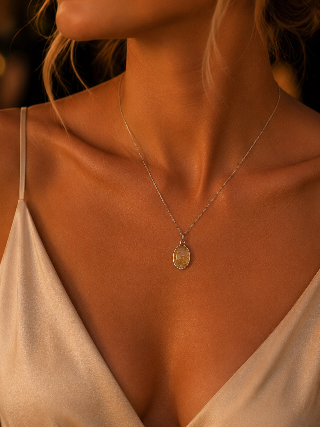 Sterling Silver Necklace with a natural rutilated quartz pendant on a person wearing a white top, with a warm, blurred background.