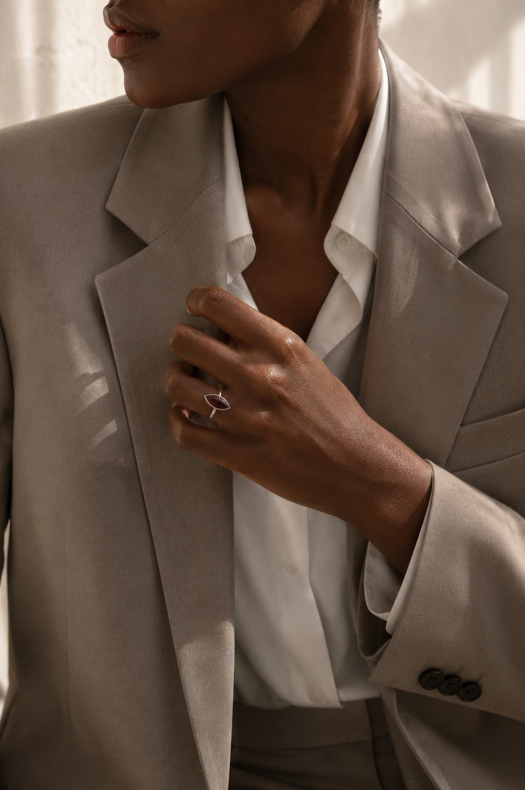 Model wearing the Amanda Ring handcrafted in solid 925 sterling silver with a natural marquise cabochon garnet by Ryã Atelier and a beige suit. 