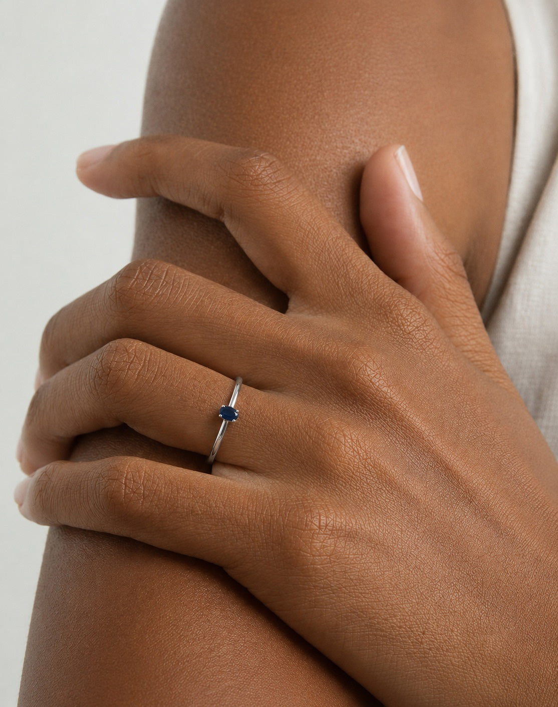 Hand model wearing the Amani Solitaire Ring handcrafted in solid 925 sterling silver with a natural oval sapphire by Ryã Atelier on her ring finger.