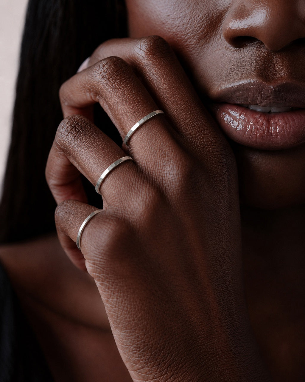 close up of models hands wearing three Asanda Thick Rings handcrafted in solid 925 sterling silver with hand-hammered faceted bands by Ryã Atelier, one on each finger.