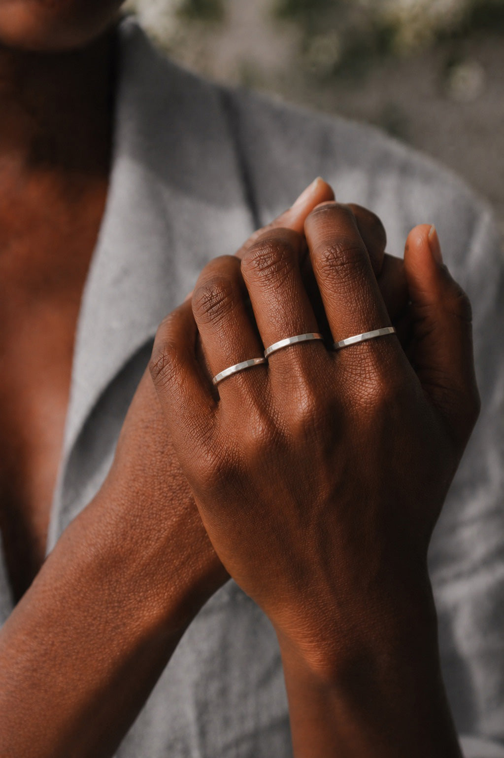 close up of models hands wearing three Asanda Thick Rings handcrafted in solid 925 sterling silver with hand-hammered faceted bands by Ryã Atelier, one on each finger.