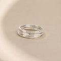 Three Asanda Thick Rings handcrafted in solid 925 sterling silver with hand-hammered faceted bands by Ryã Atelier, on a beige background.