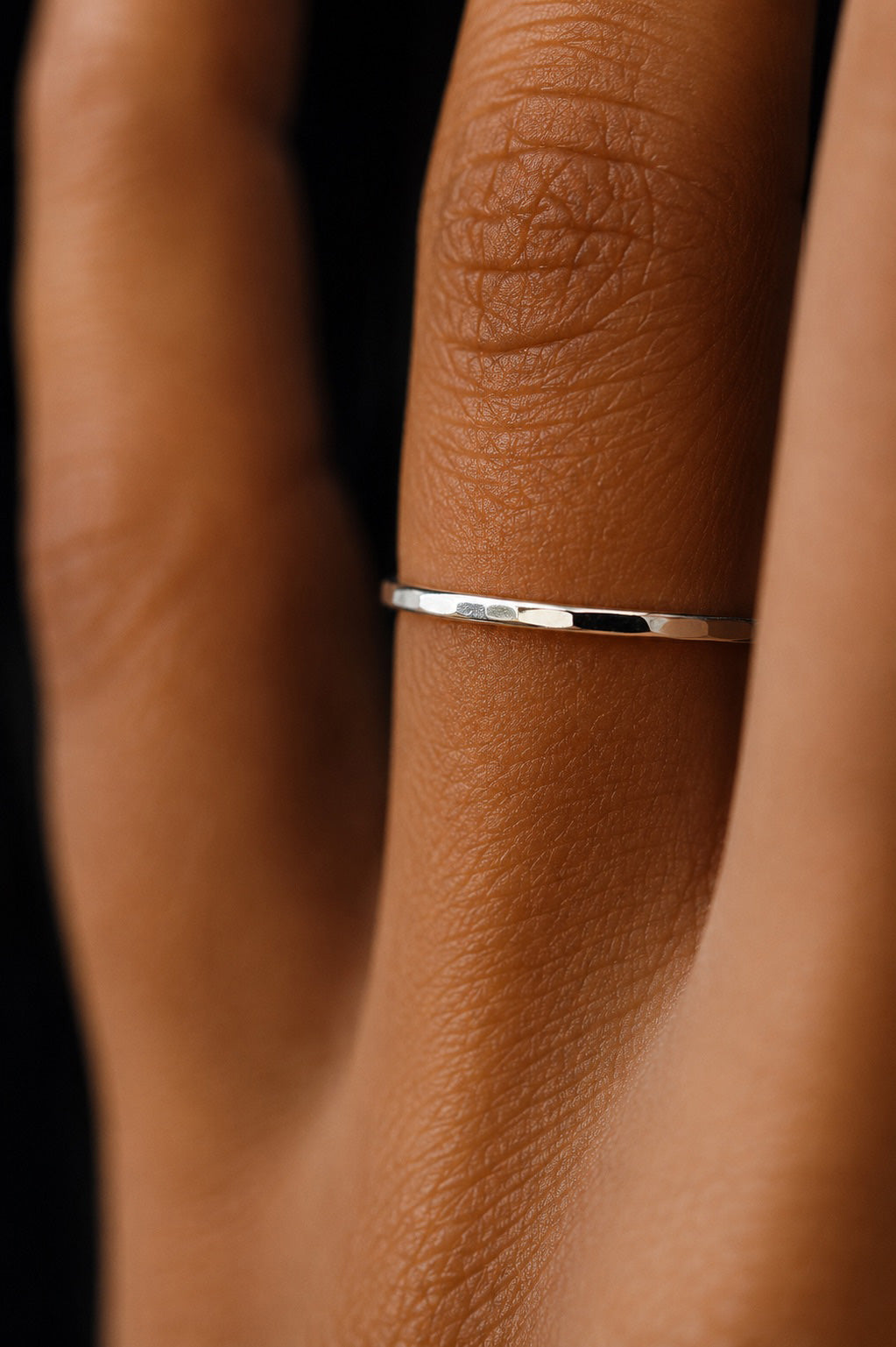 extreme close up of fingers wearing Asanda Thin Ring handcrafted in solid 925 sterling silver featuring a minimalist hand-hammered faceted stacking band by Ryã Atelier.