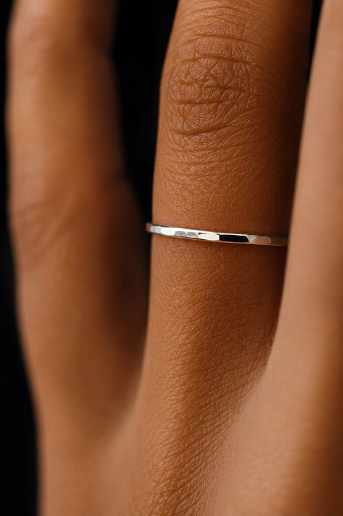 extreme close up of fingers wearing Asanda Thin Ring handcrafted in solid 925 sterling silver featuring a minimalist hand-hammered faceted stacking band by Ryã Atelier.