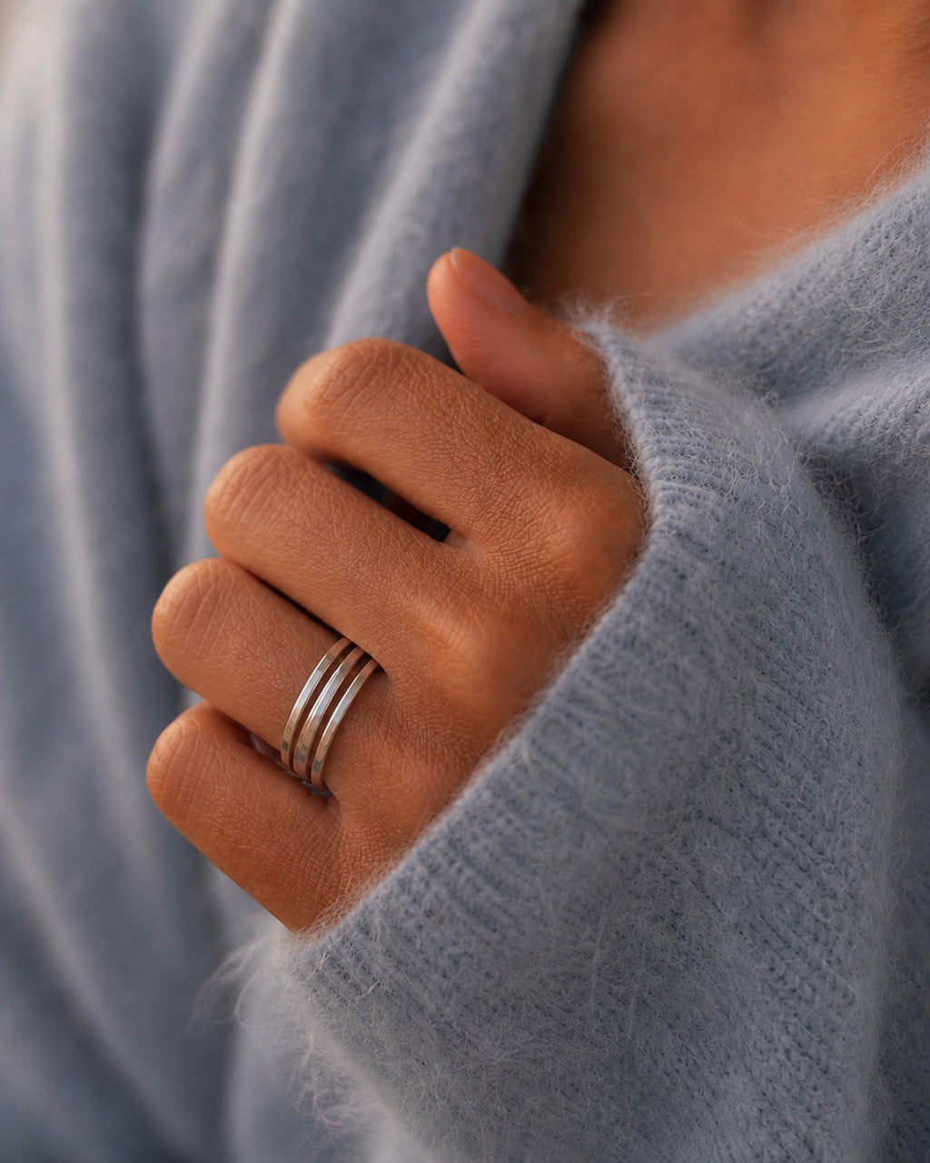 Close-up of a hand wearing Three Asanda Thin Rings handcrafted in solid 925 sterling silver with hand-hammered faceted bands by Ryã Atelier.