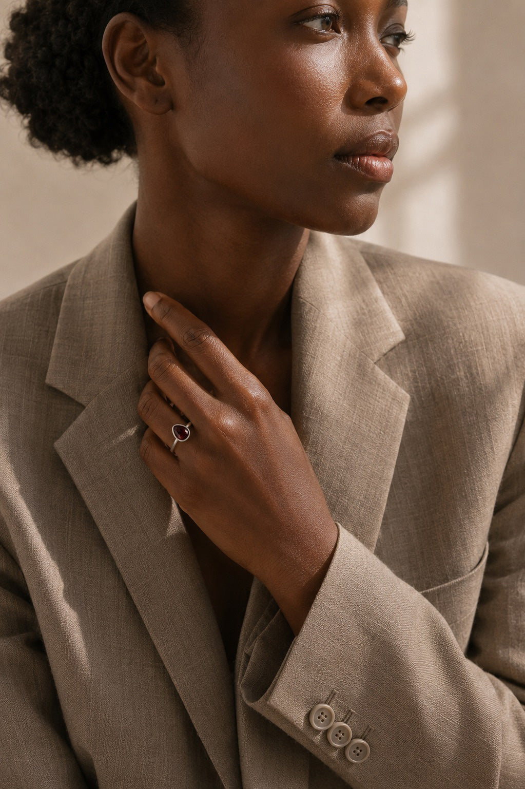 Model wearing the Avethandwa Ring handcrafted in solid 925 sterling silver with a natural pear-shaped garnet by Ryã Atelier in a suit. 