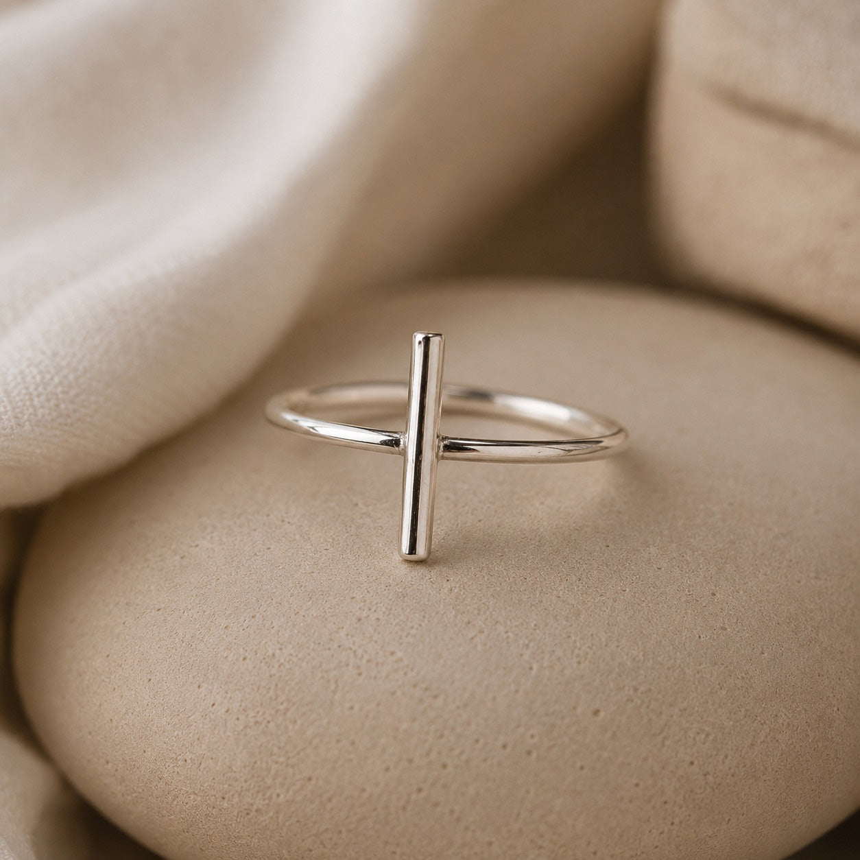 Dali Ring handcrafted in solid 925 sterling silver featuring a minimalist bar design by Ryã Atelier on a beige stone. 