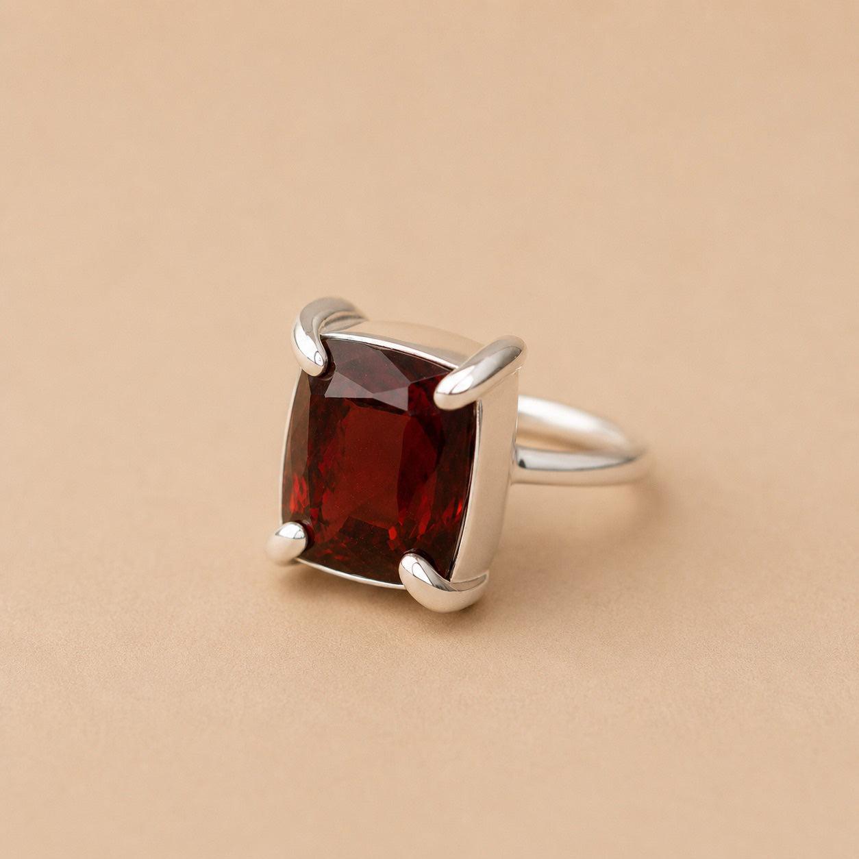 Holly Ring handcrafted in solid 925 sterling silver featuring a natural emerald cut garnet in a contemporary four-claw setting by Ryã Atelier on a beige background.