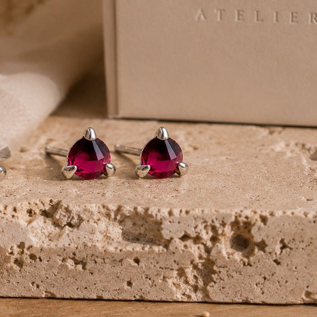 Sterling Silver earrings with red garnets  on a beige surface with 'RYA ATELIER' branding.