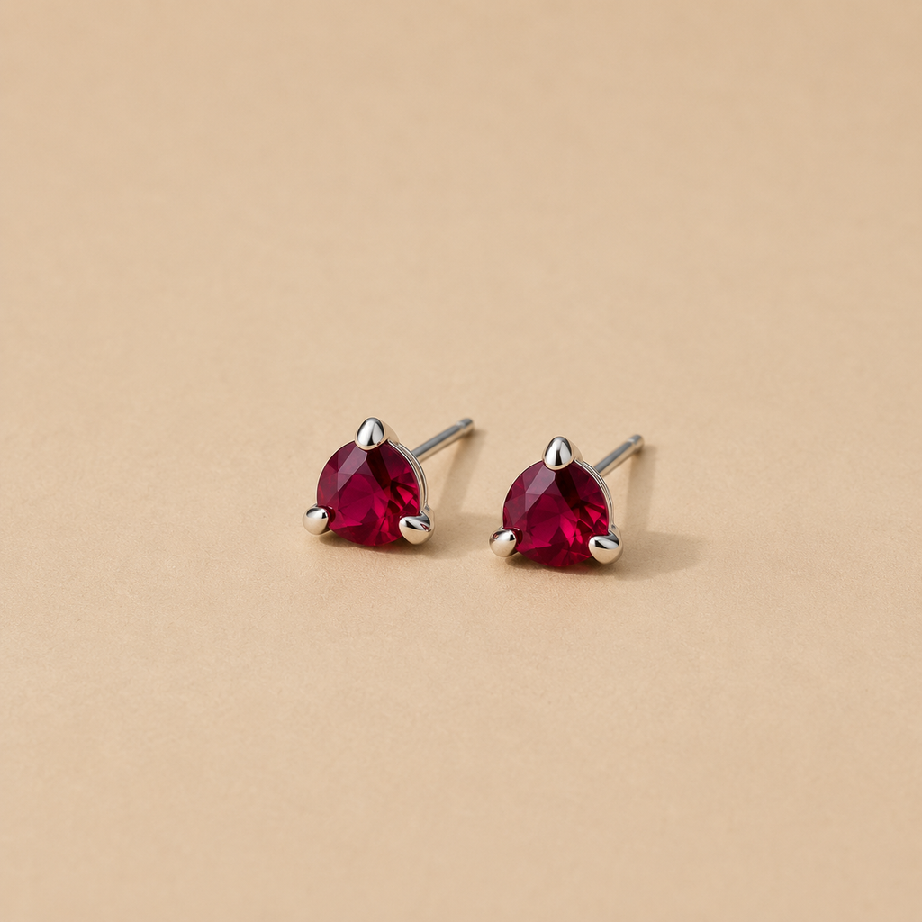 Iminathi earrings handcrafted Sterling silver stud earrings with red garnets on a beige background by Ryā Atelier.