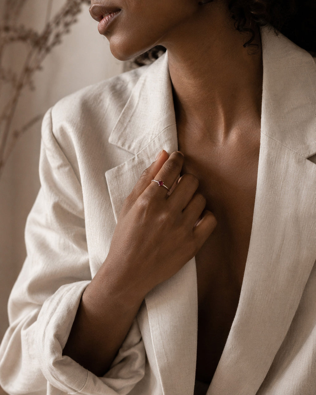 Person wearing Sterling Silver ring with a natural red garnet and a light-colored blazer with a neutral background