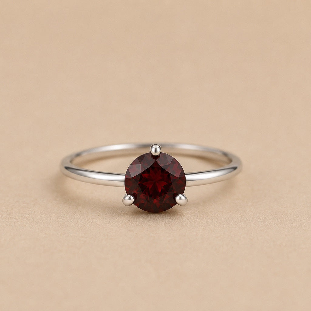 Sterling Silver ring with a natural red garnet on a beige background