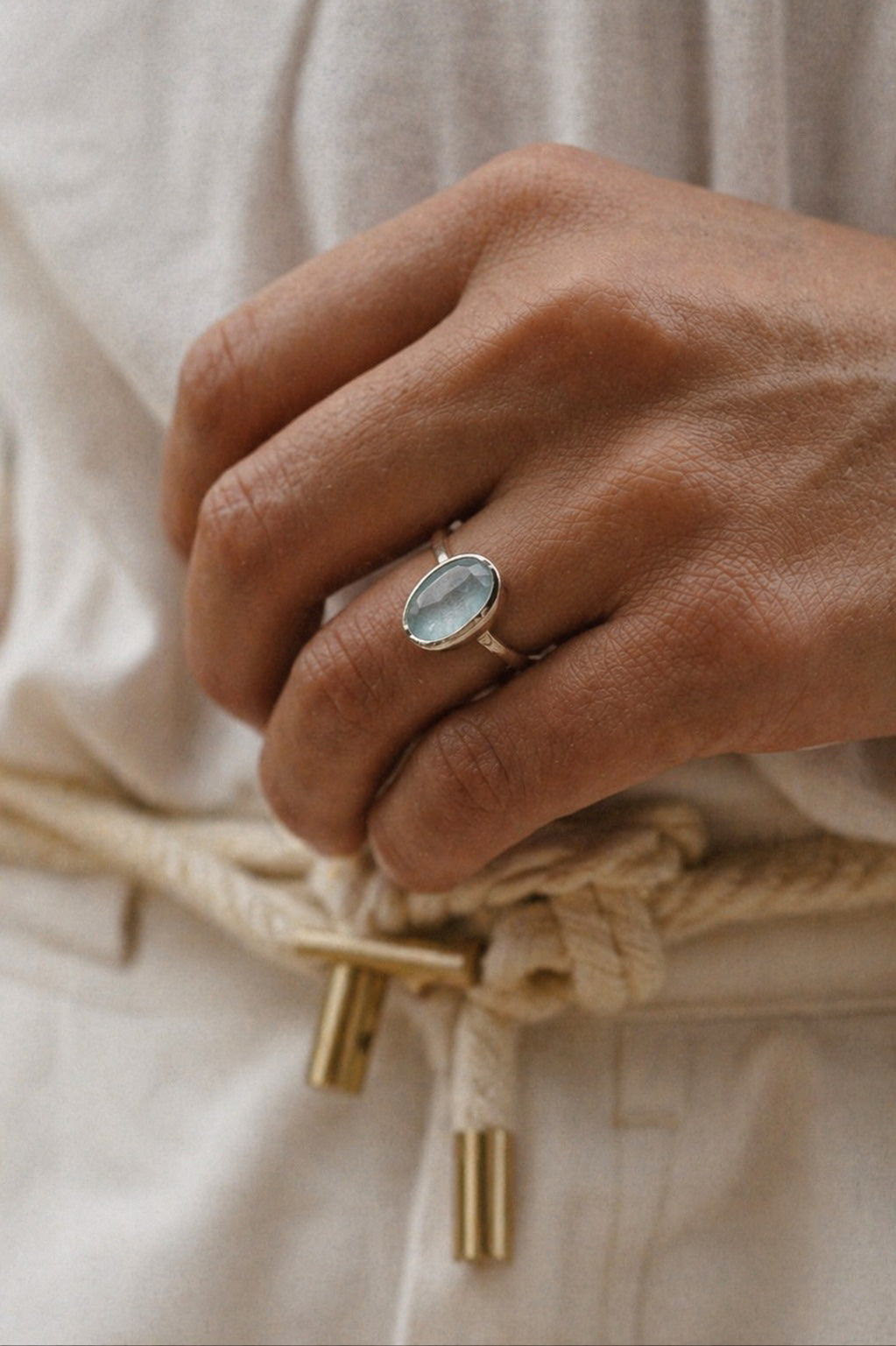 Close up of hand with the Imka Ring handcrafted in solid 925 sterling silver featuring a natural oval aquamarine in a bezel setting by Ryã Atelier.