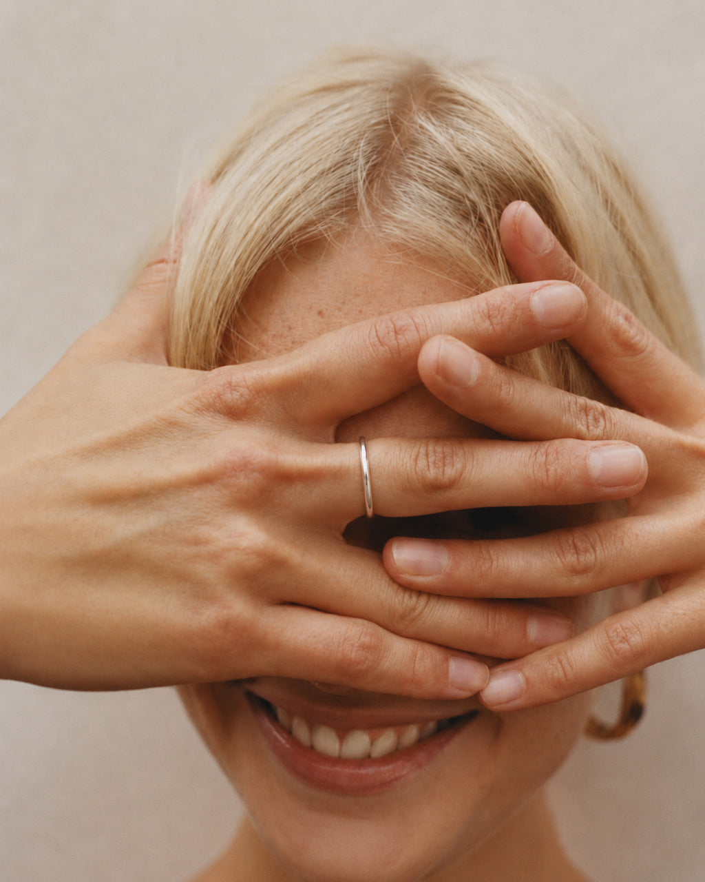 woman with hands covering face, wearing a handcrafted solid 925 sterling silver Lesedi ring from Ryā Atelier, against a neutral background