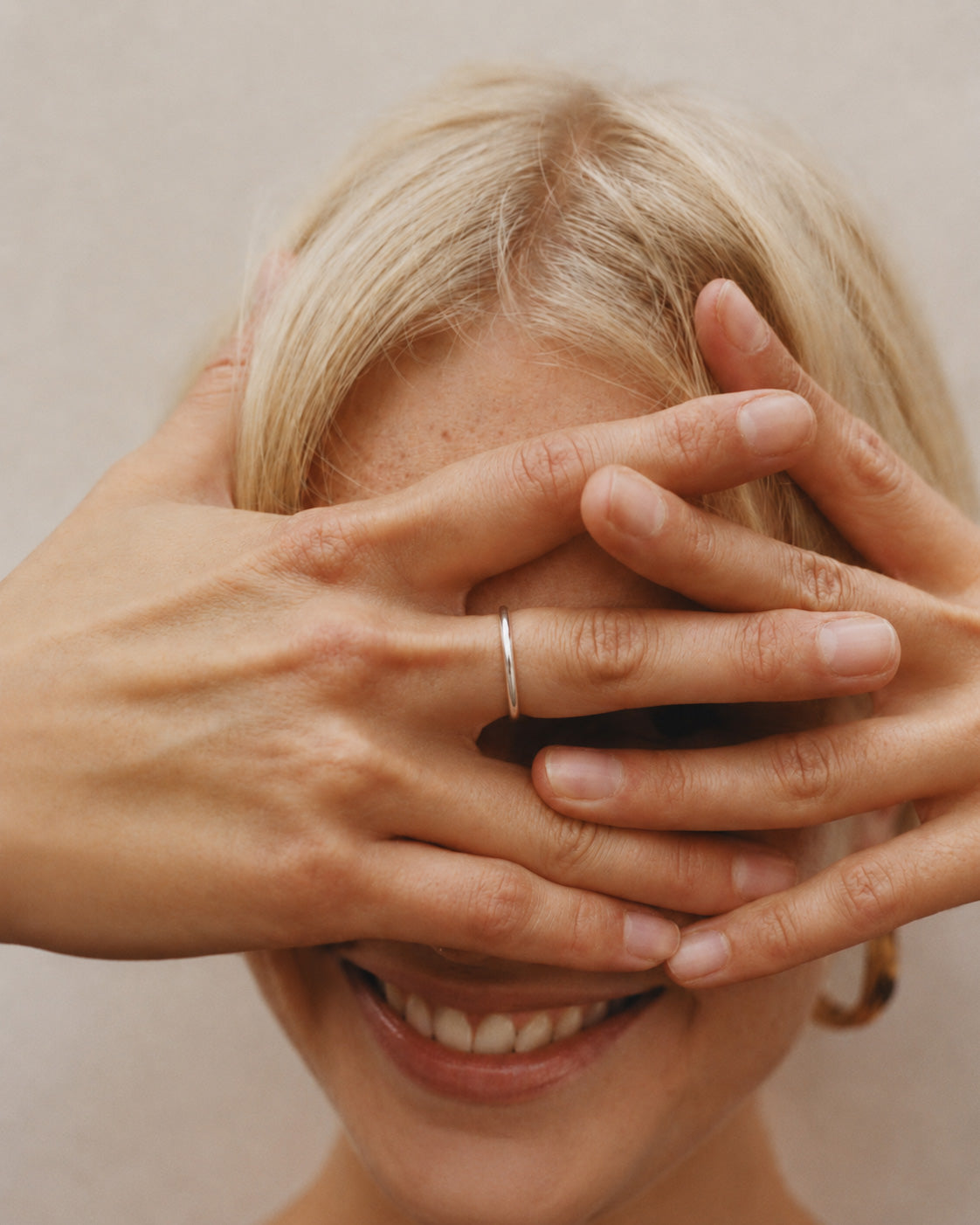 woman with hands covering face, wearing a handcrafted solid 925 sterling silver Lesedi ring from Ryā Atelier, against a neutral background