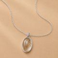 Sterling Silver necklace with a natural gold rutilated quartz pendant on a beige background