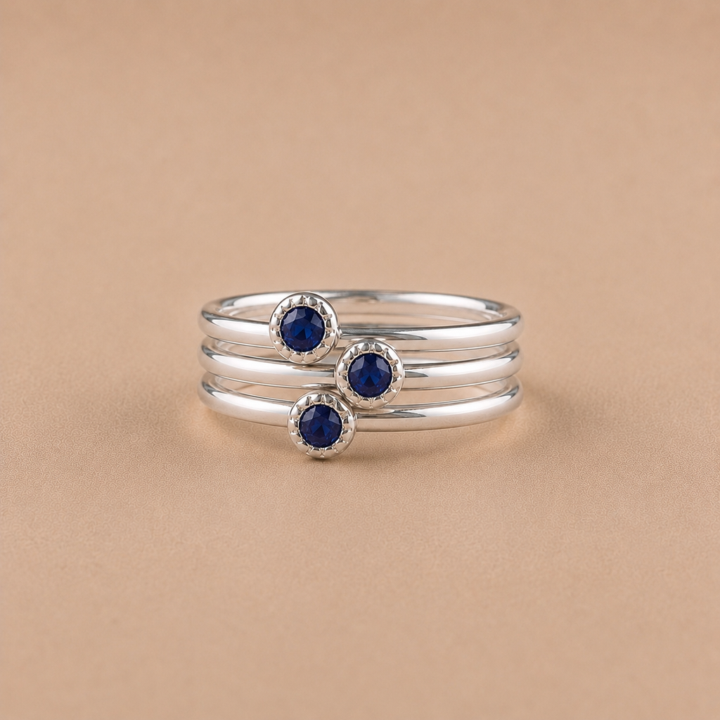 3 Sterling Silver ring stack with sapphire gemstones on a beige background