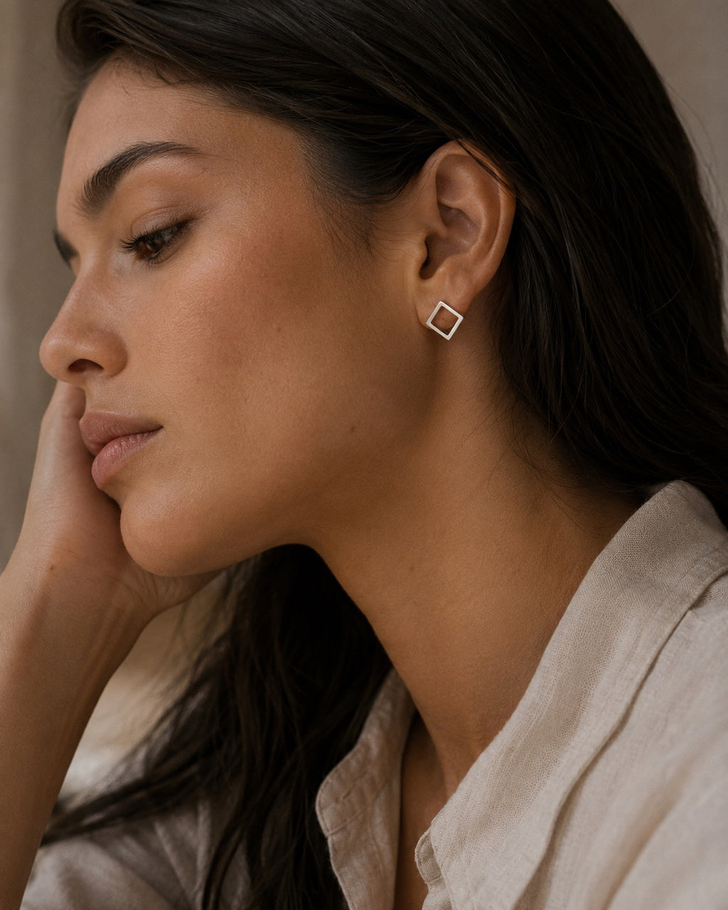 Close-up of a woman wearing a sterling silver square earring with a neutral background