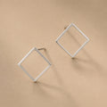 Sterling Silver square stud earrings on a beige background