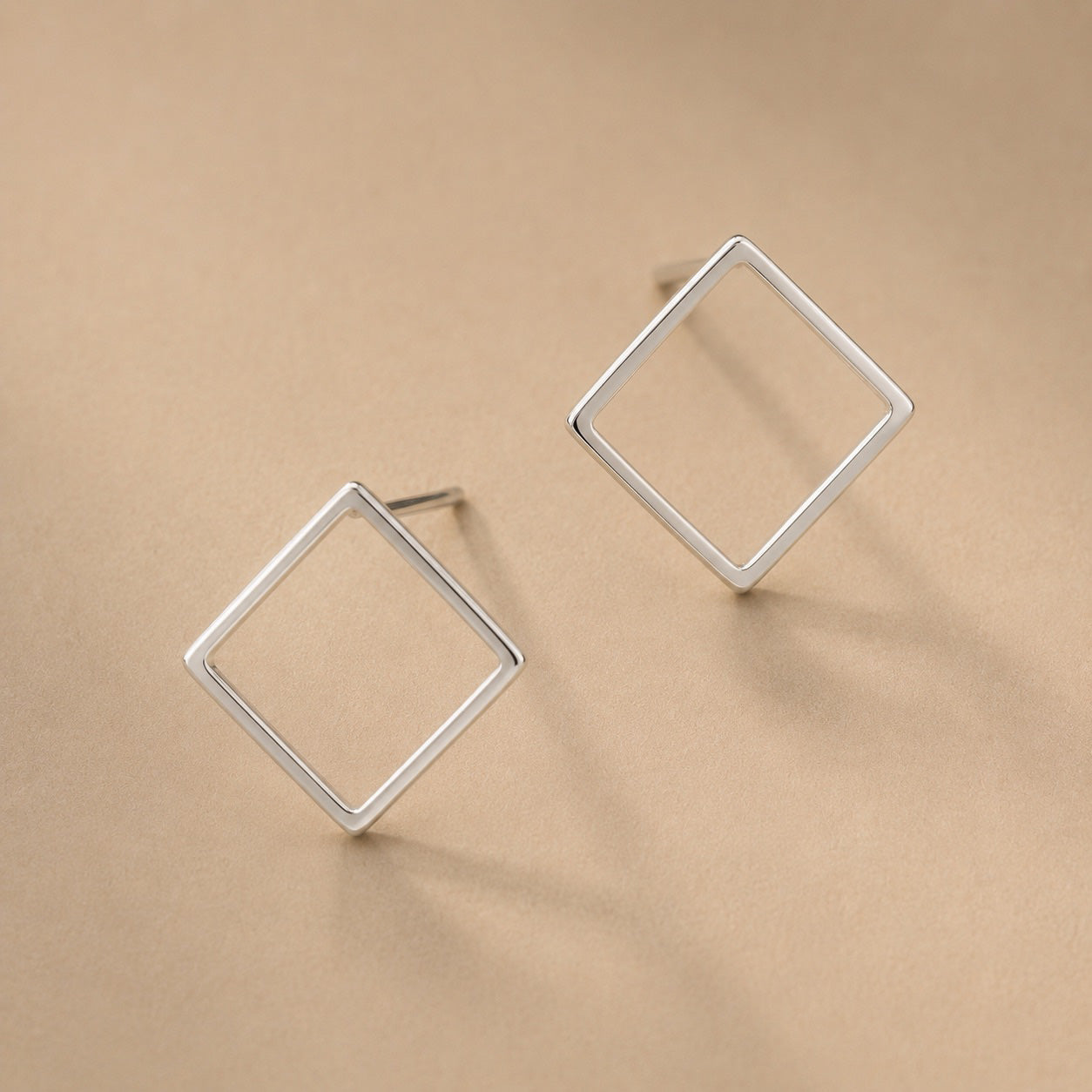 Sterling Silver square stud earrings on a beige background