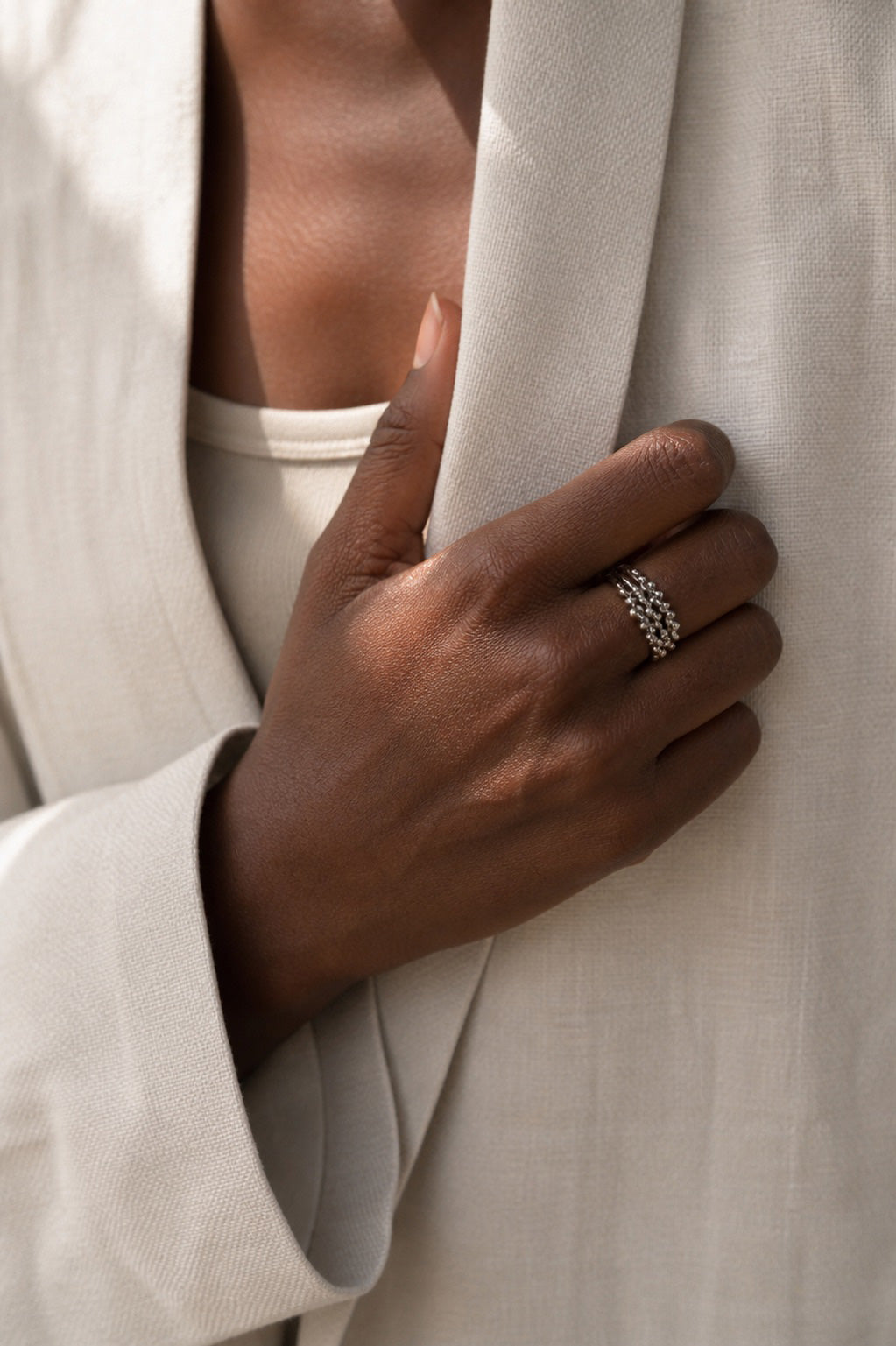 Hand wearing a sterling silver 3 ring stack with a beaded design with a neutral background