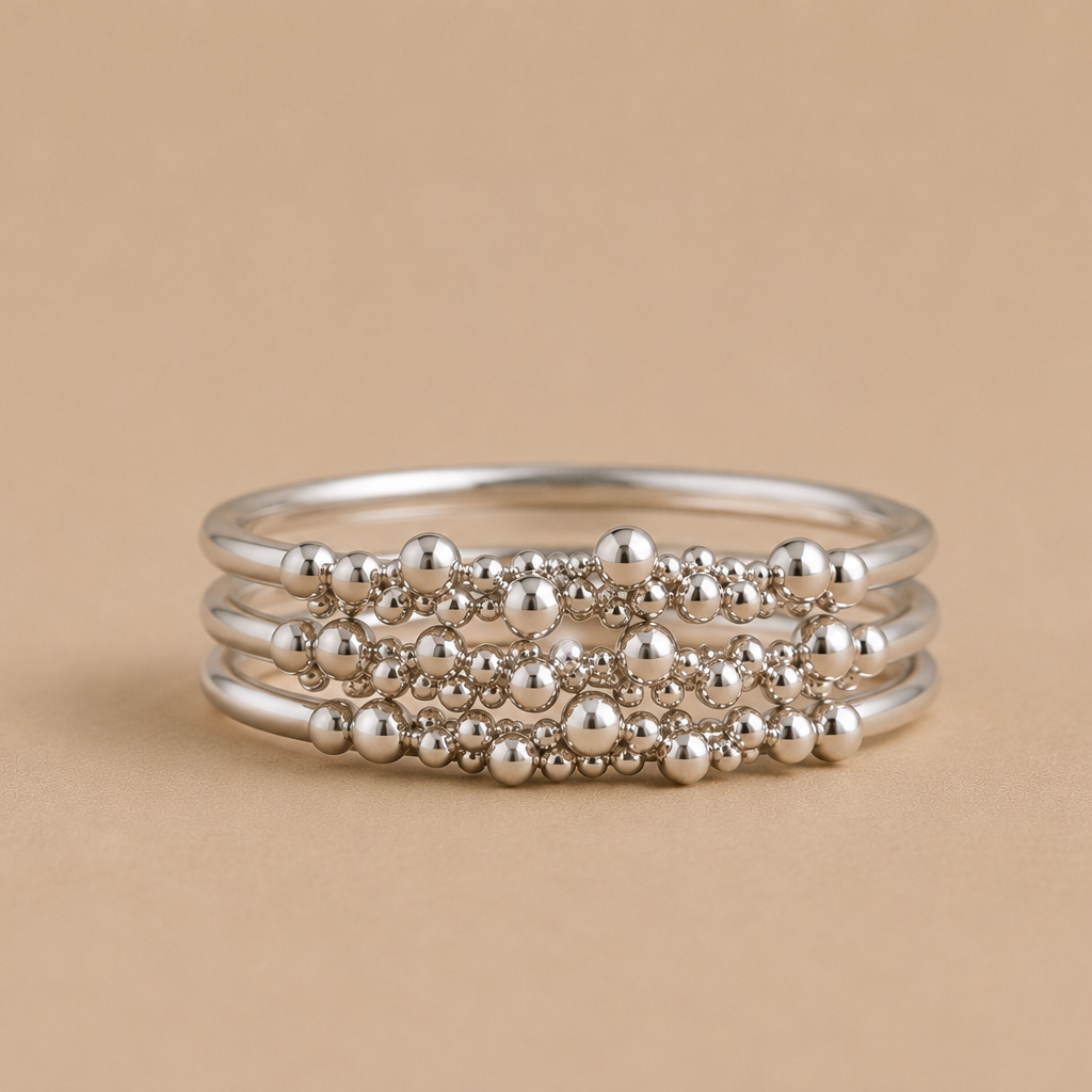 Stack of 3 sterling silver beaded rings on a beige background