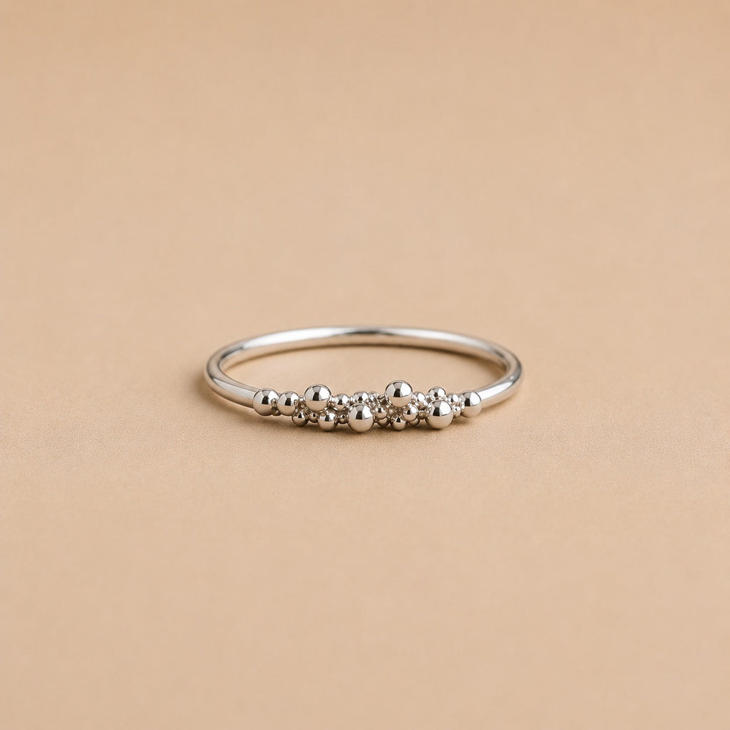 Sterling Silver ring with organic raindrop bead detailing on a beige background