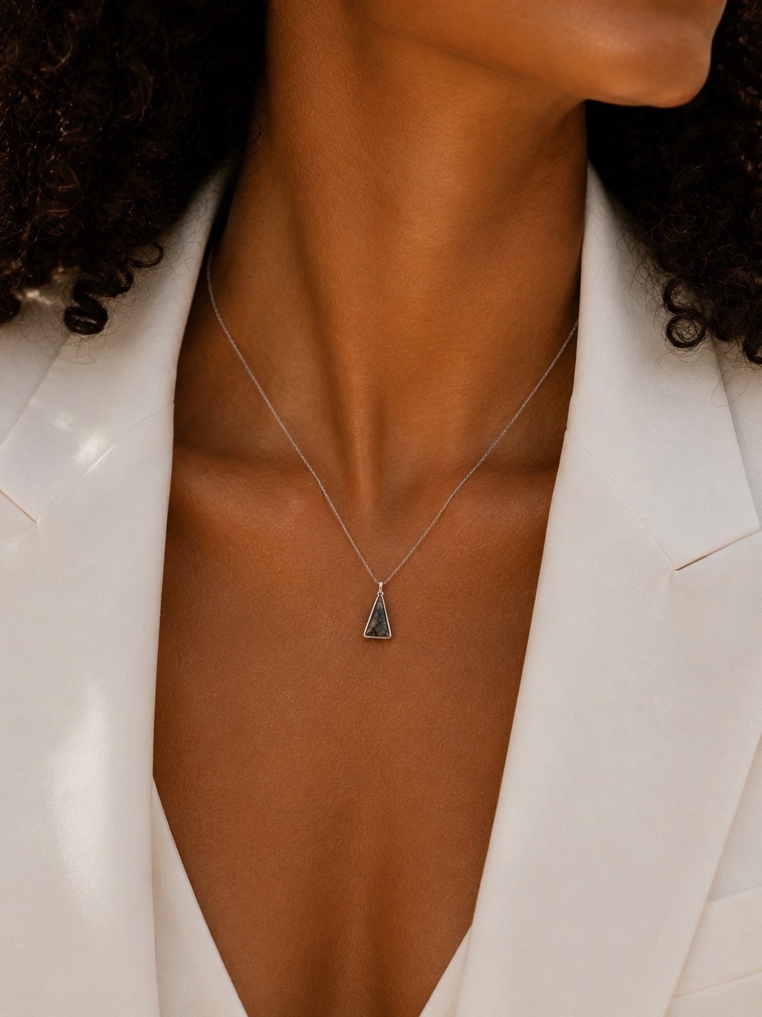 Sterling Silver Necklace with a triangular tourmalated quartz pendant worn by a person in a white blazer.