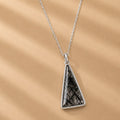 Sterling Silver Necklace with a triangular tourmalated quartz pendant on a beige fabric background