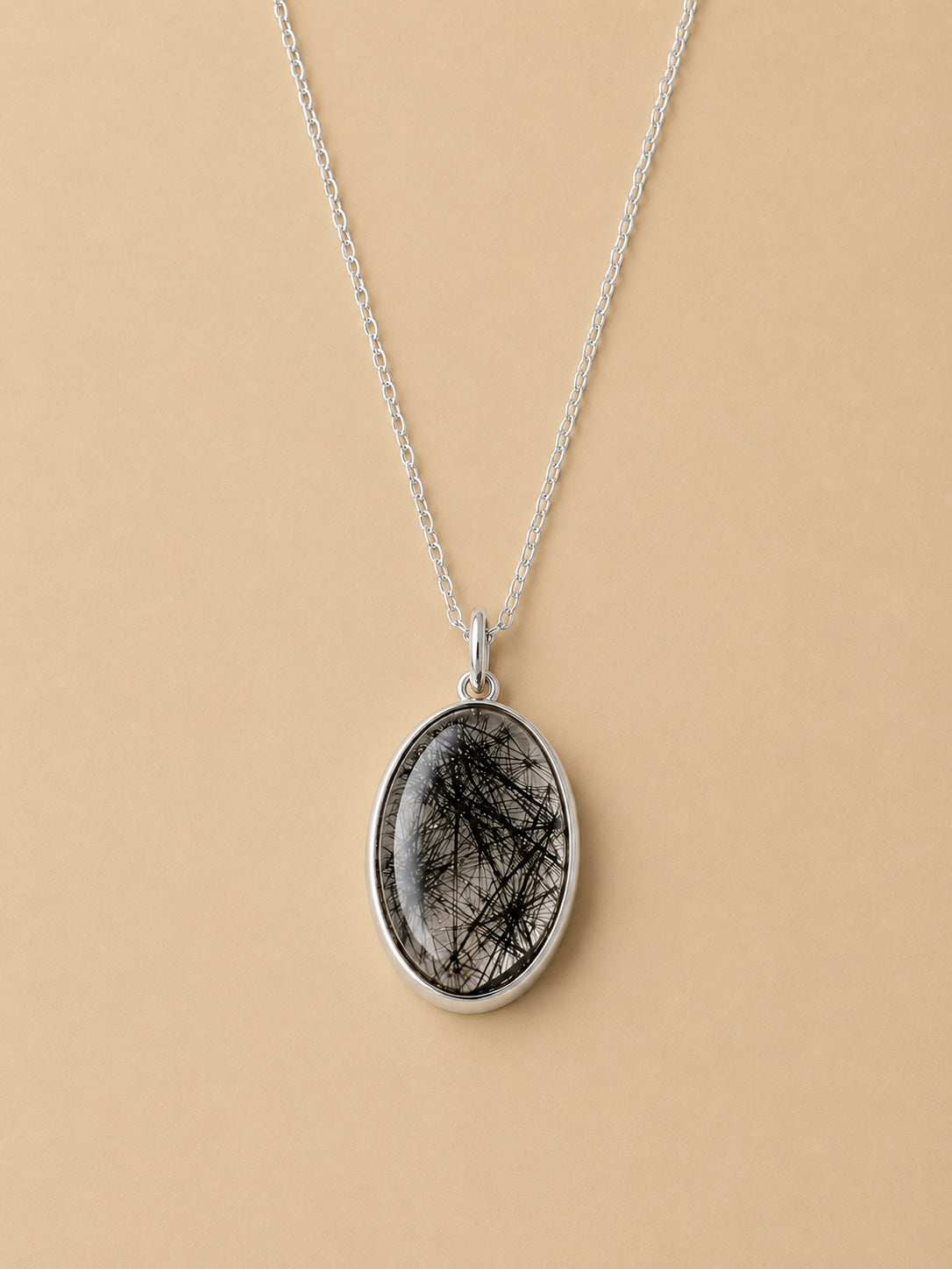 Sterling Silver Necklace with an oval tourmalated quartz pendant on a beige background