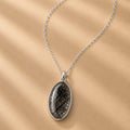 Sterling Silver necklace with an oval tourmalated quartz pendant on a beige background