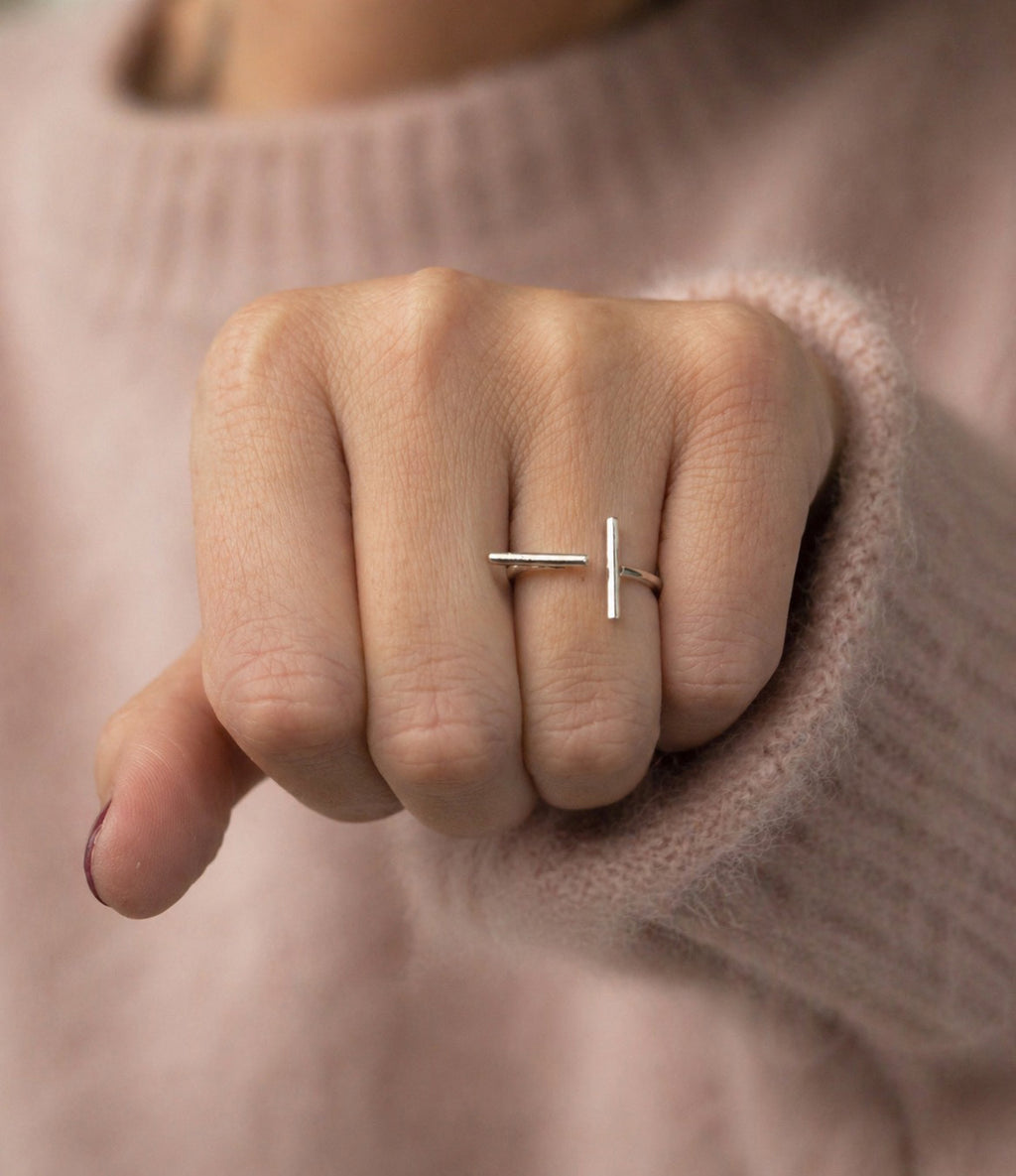 Hand wearing a solid 925 sterling silver contemporary minimalist broken bar ring by Ryā Atelier with a soft pink sweater background