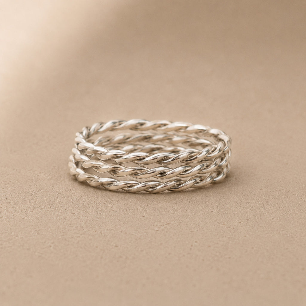 Stack of sterling silver twisted rings on a beige background