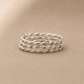Stack of sterling silver twisted rings on a beige background