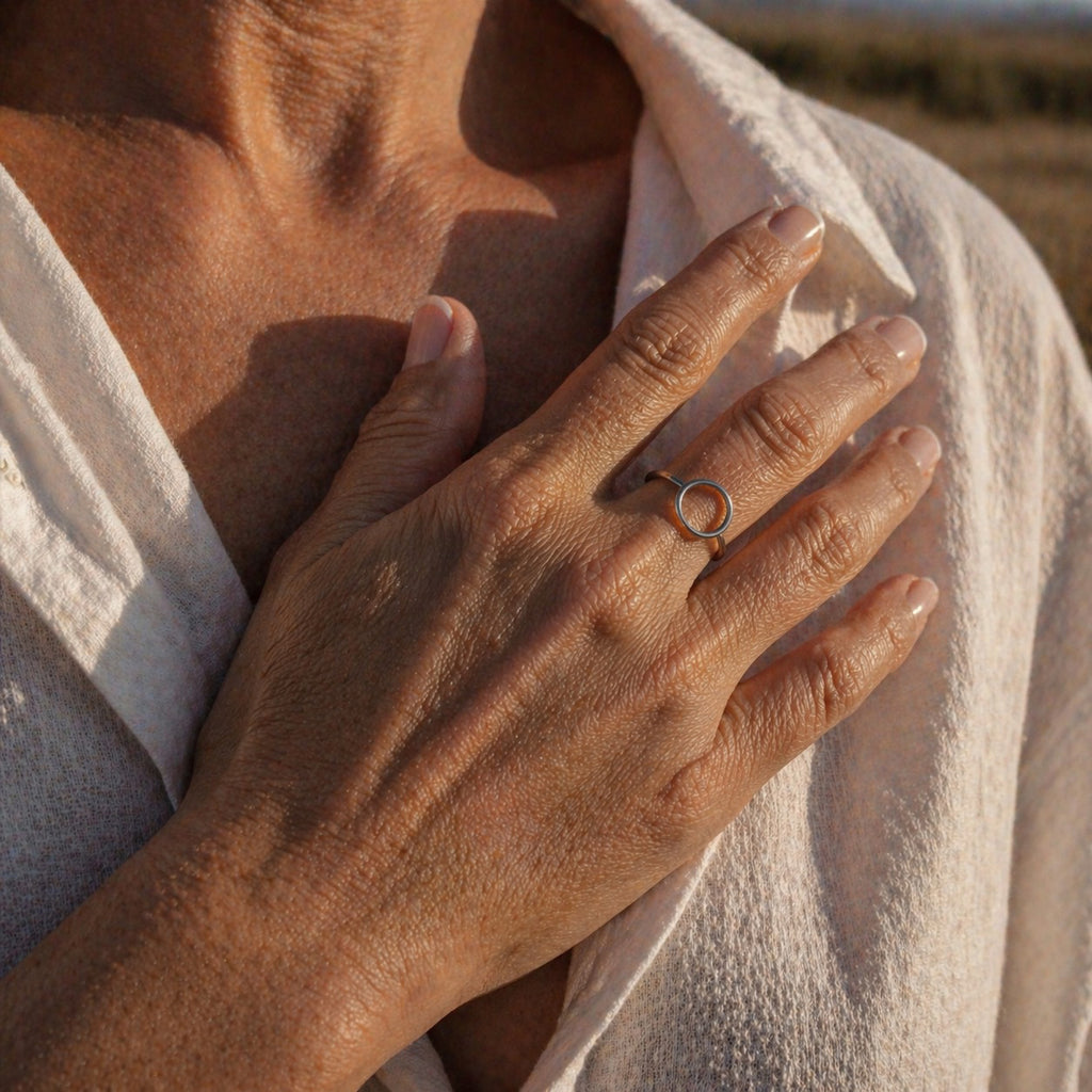 Close-up of an older person's hand with a sterling silver ring with a circle design on a blurred natural background