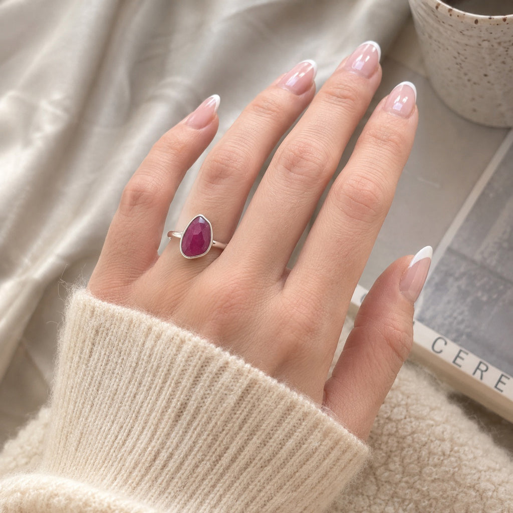 Close up of a hand wearing the Thabisa Ring handcrafted in solid 925 sterling silver with a natural pear cut pink ruby by Ryã Atelier.
