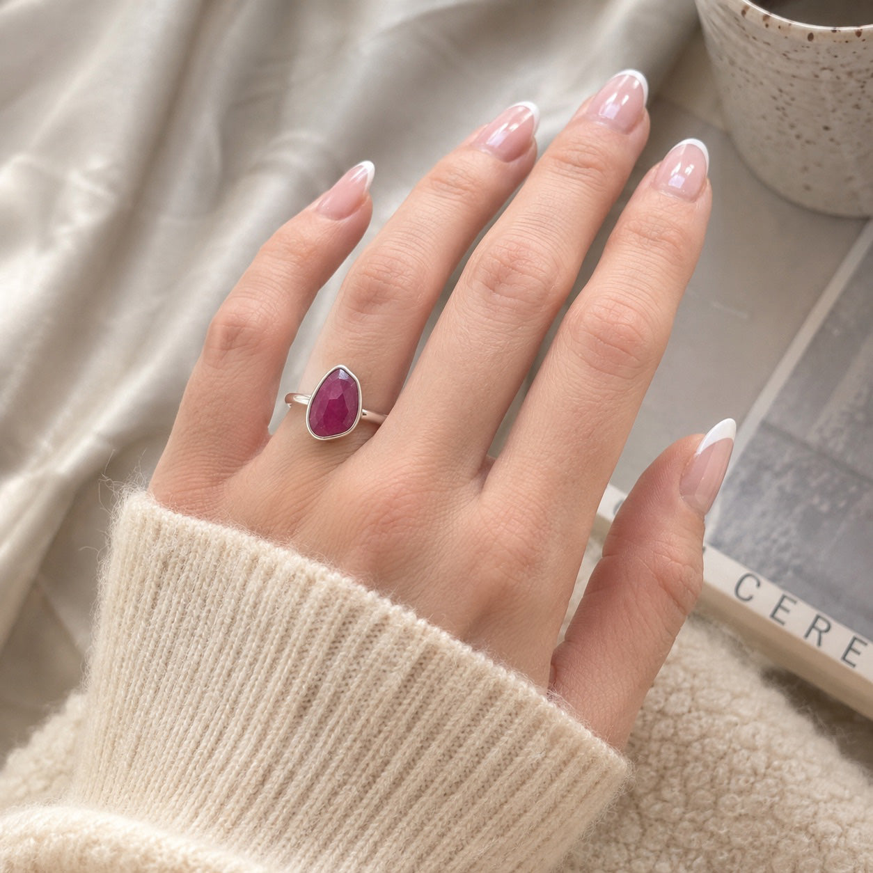 Close up of a hand wearing the Thabisa Ring handcrafted in solid 925 sterling silver with a natural pear cut pink ruby by Ryã Atelier.