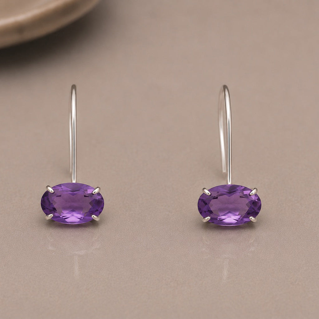 Pair of purple amethyst earrings set in sterling silver on a beige surface