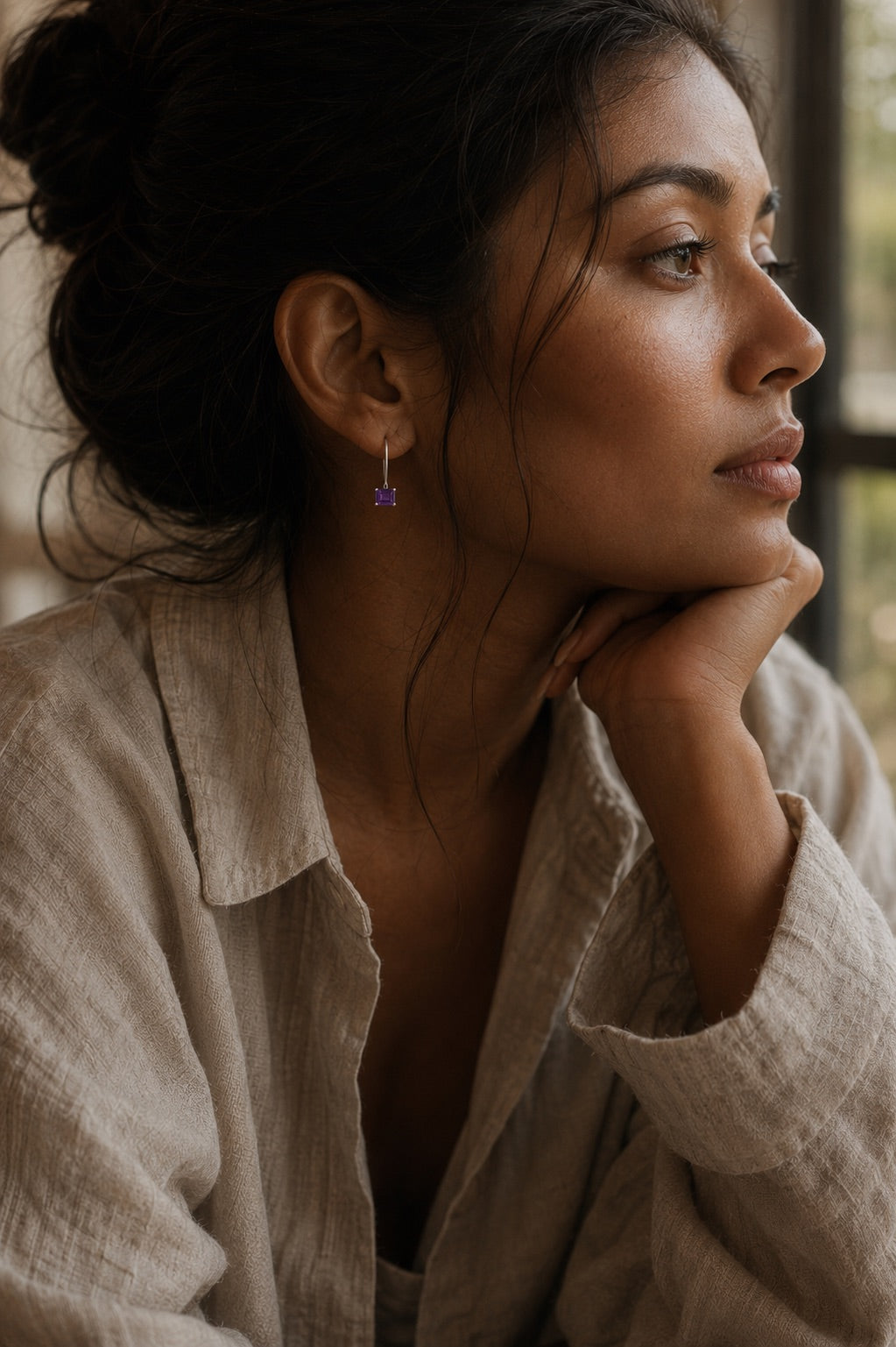 Women wearing a beige linen shirt and a pair of rectangular purple amethyst earrings set in sterling silver with a blurred background