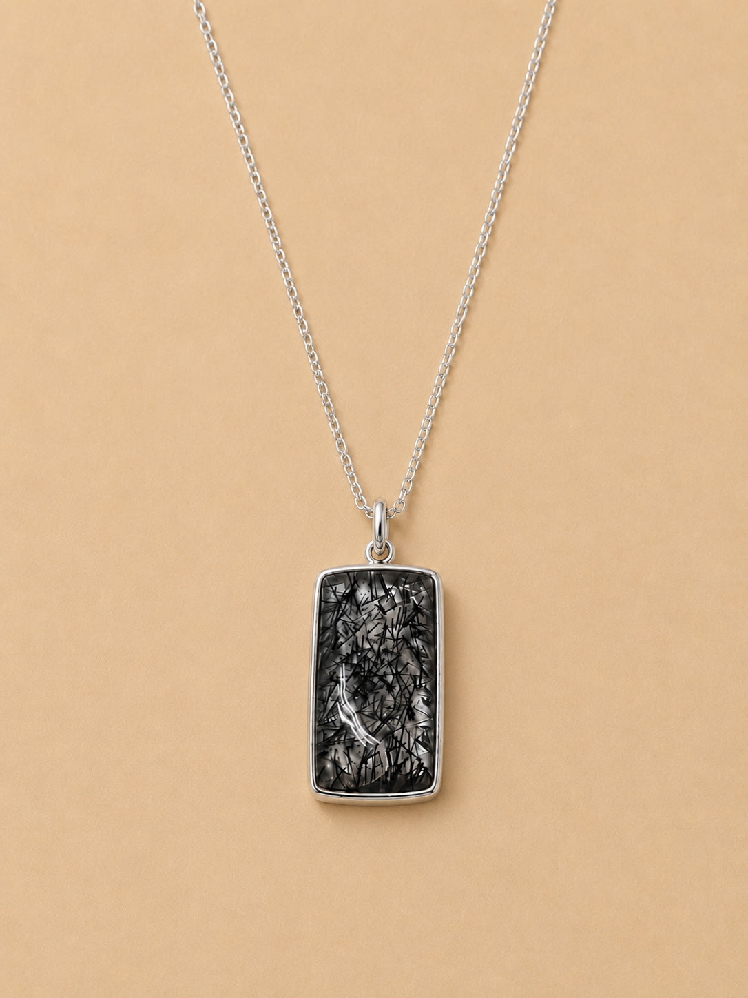 Sterling Silver necklace with a Tourmalated Quartz pendant on a beige background