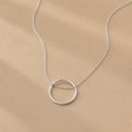 Sterling Silver necklace with a circle pendant on a beige background