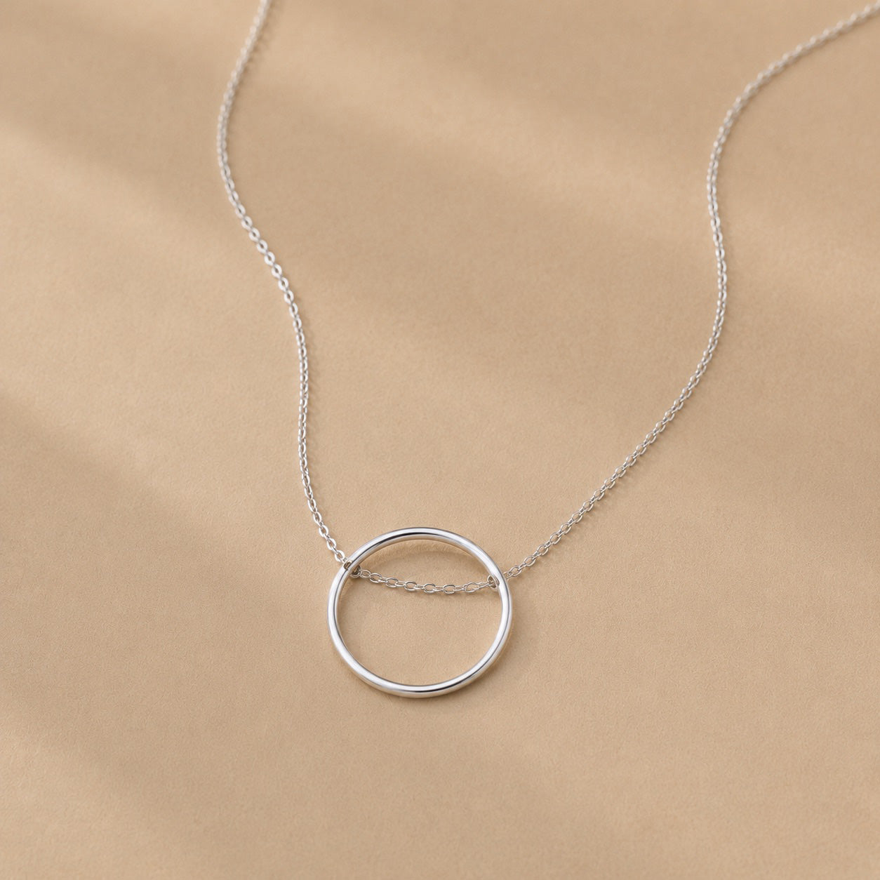 Sterling Silver necklace with a circle pendant on a beige background